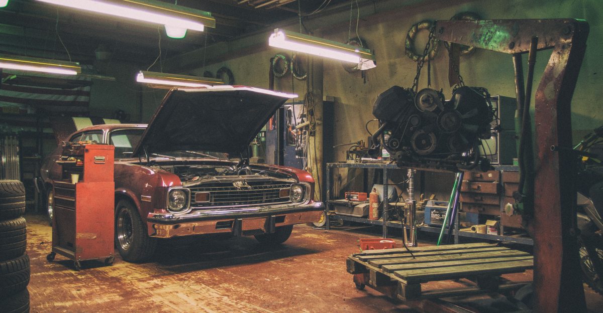 Vintage interior of a car repair shop with an old red American car and car engine on the crane The automobile is ready for an engine replacement Photographed by Martin Vorel