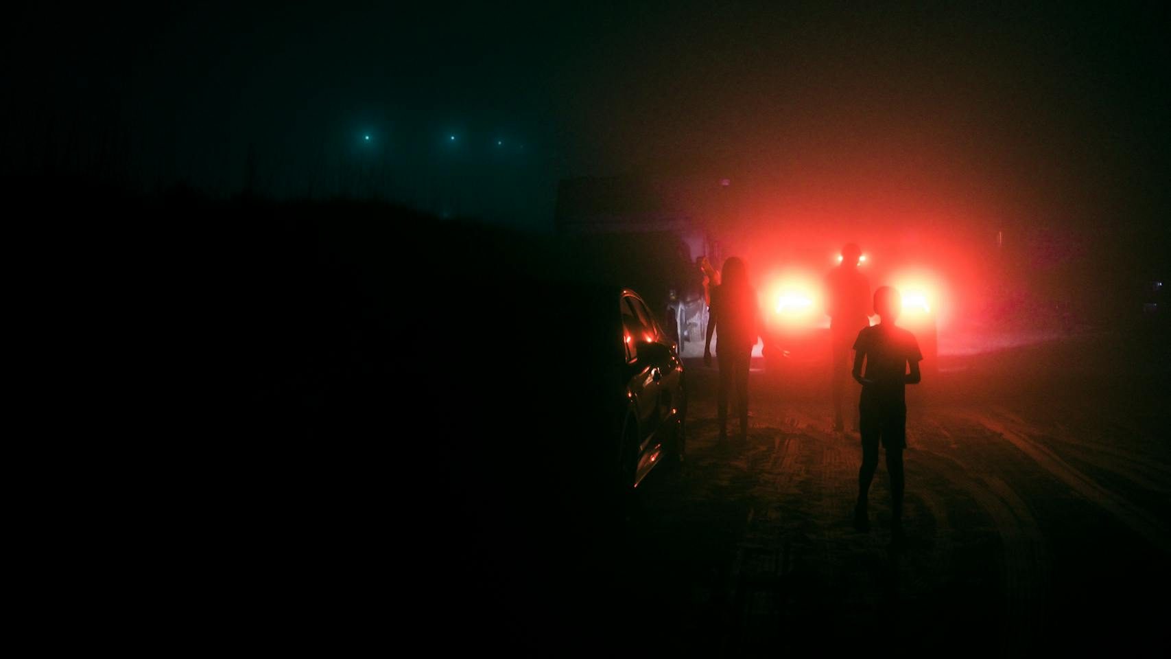 Foggy night scene with mysterious red lights and silhouettes in Brownsville, TX.