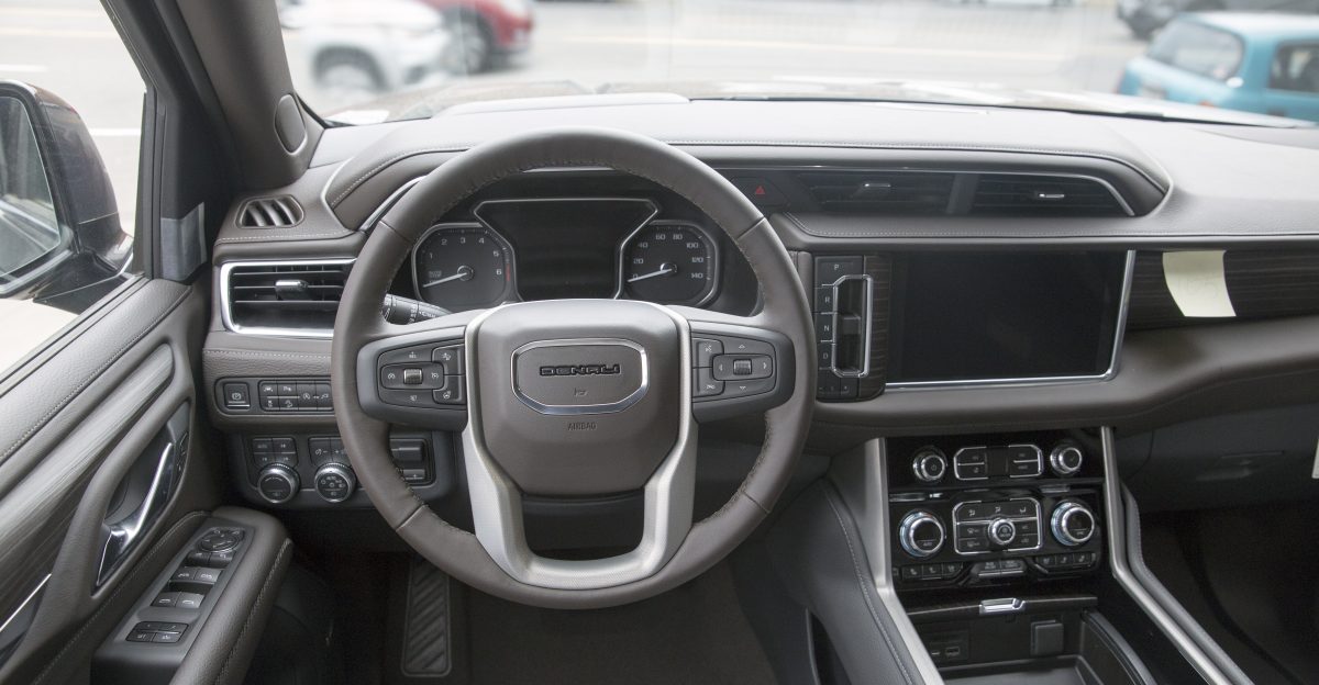 The dashboard of a 2021 GMC Yukon Denali Dark Walnut and Ash Gray interior Hunter Metallic exterior Optional power sliding floor console Assembled in Arlington TX