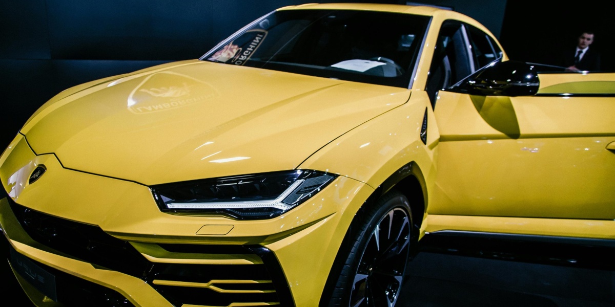 A stunning yellow luxury SUV on display at an auto show under bright lights.