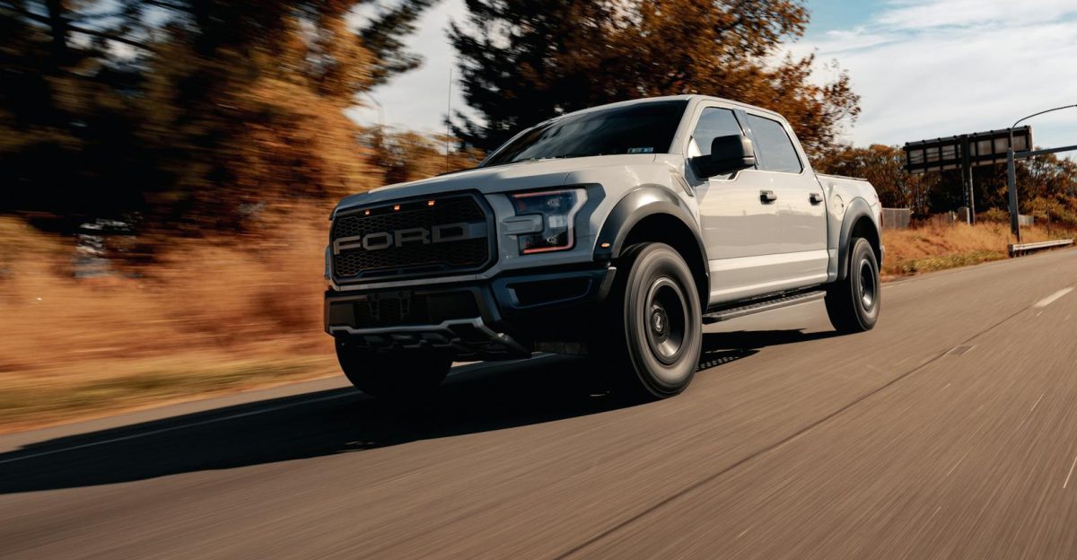 A Ford F-150 driving on a scenic highway surrounded by trees and blue skies