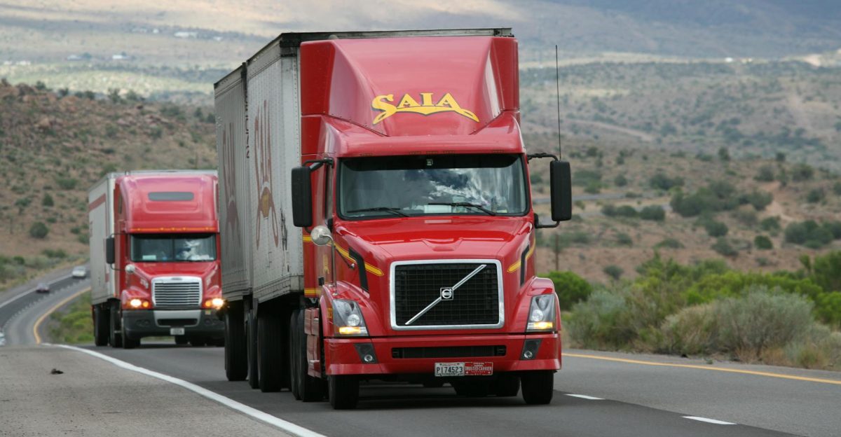Red trucks driving through a scenic desert landscape showcasing transportation logistics
