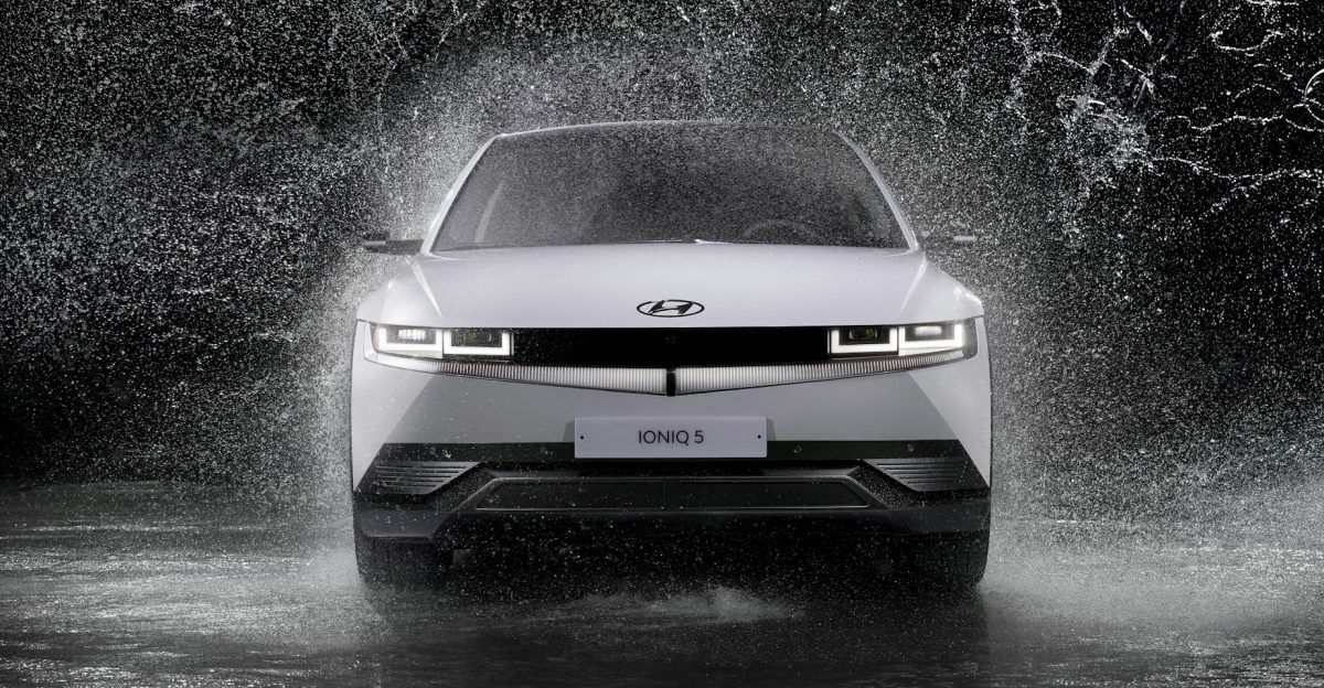 Dynamic front view of a Hyundai Ioniq 5 splashing through rain captured in black and white