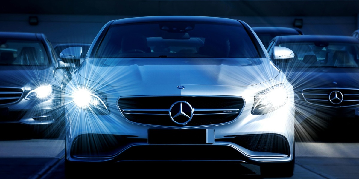 Front view of a lineup of Mercedes-Benz cars with bright headlights, showcasing luxury and elegance.