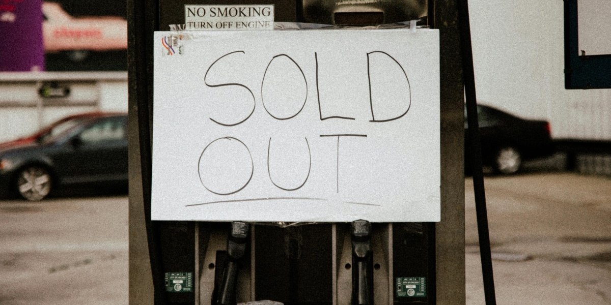 A gas pump at an urban station displaying a 'Sold Out' sign, illustrating fuel shortage.