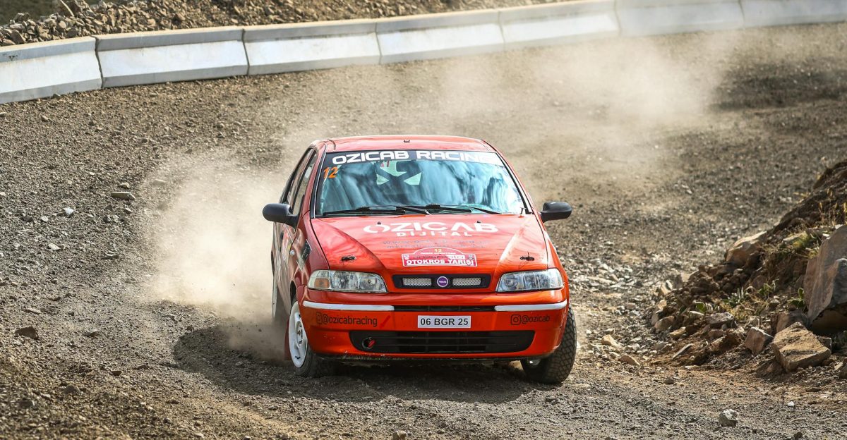 Fiat Palio car speeding through a dusty gravel rally track with skillful maneuvering