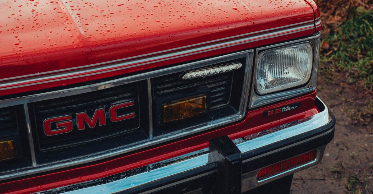 Front view of a red GMC SUV with raindrops on the hood showcasing a wet and rainy atmosphere