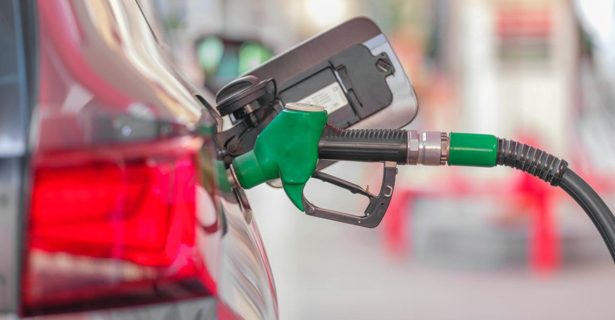 A close-up view of a fuel pump nozzle inserted into a car s tank at a gas station