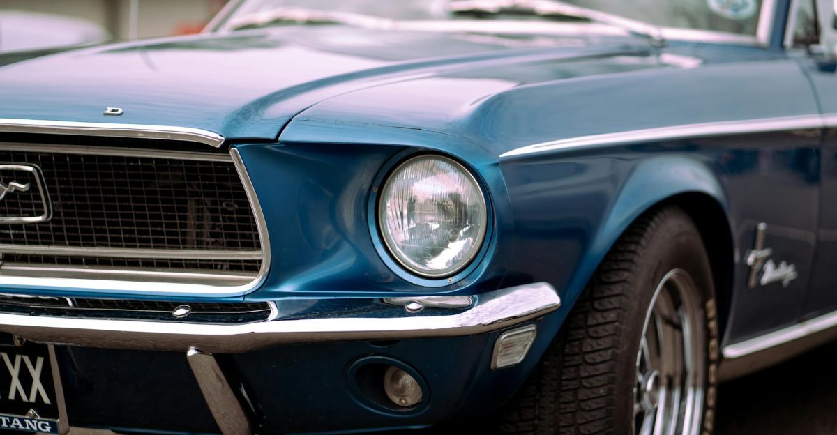 Detailed close-up of a vintage blue Ford Mustang showcasing its iconic design and headlight