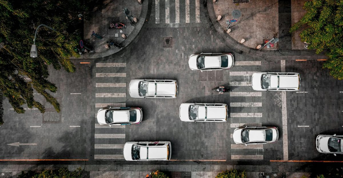 Drone shot of cars at a busy urban intersection surrounded by greenery