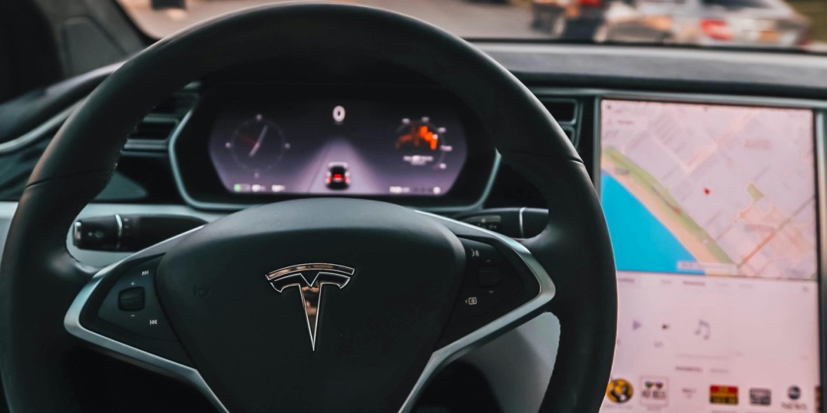 Interior view of a Tesla Model X steering through palm-lined streets of Santa Monica at twilight.
