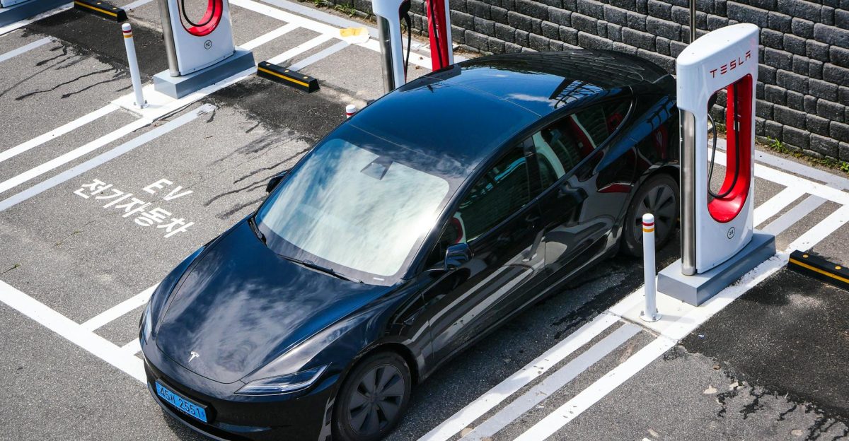 A black Tesla parked at a charging station in an urban setting
