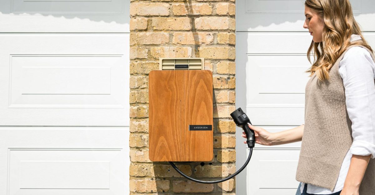 A woman uses a home electric vehicle charger mounted on a brick wall