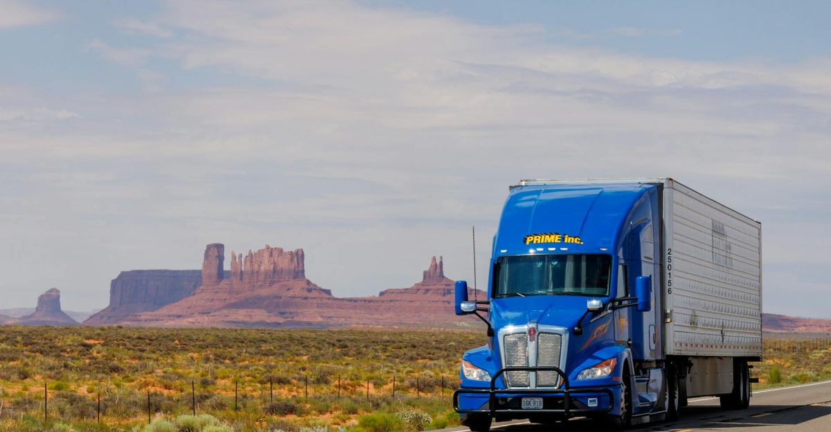 A blue truck travels on the highway with Monument Valley s iconic mesas in the background