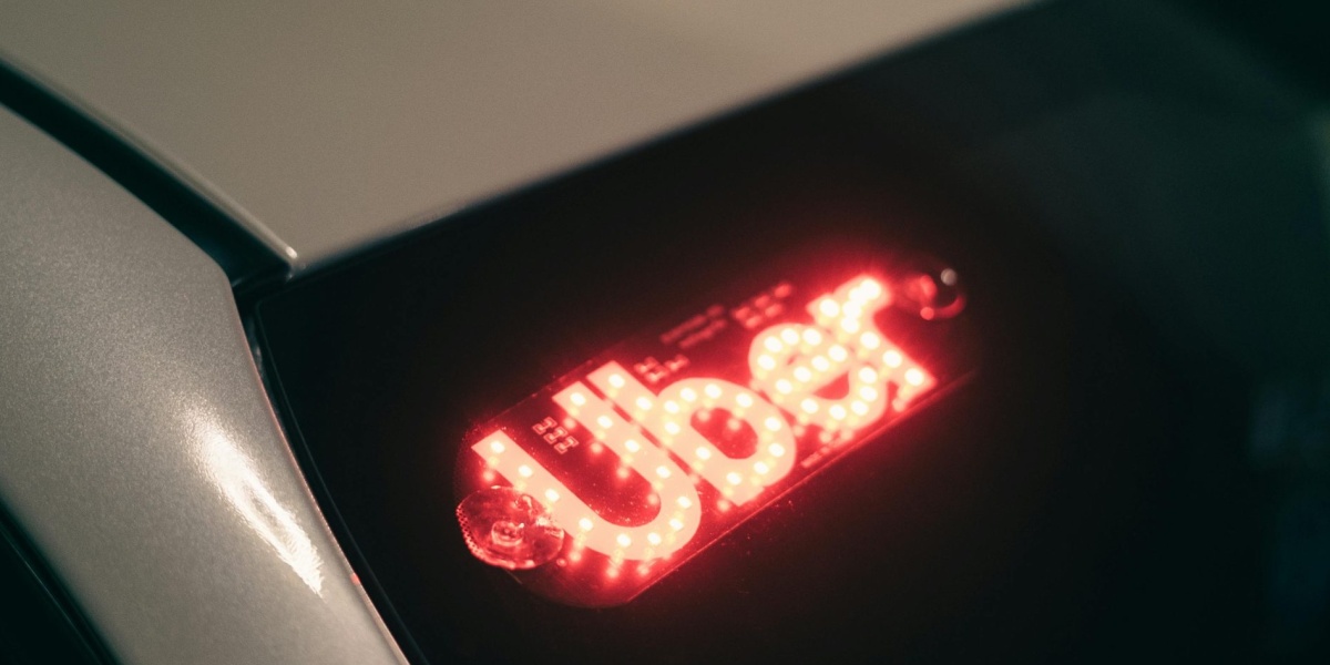 Close-up of a ride-sharing car with a bright red illuminated sign for night-time travel.