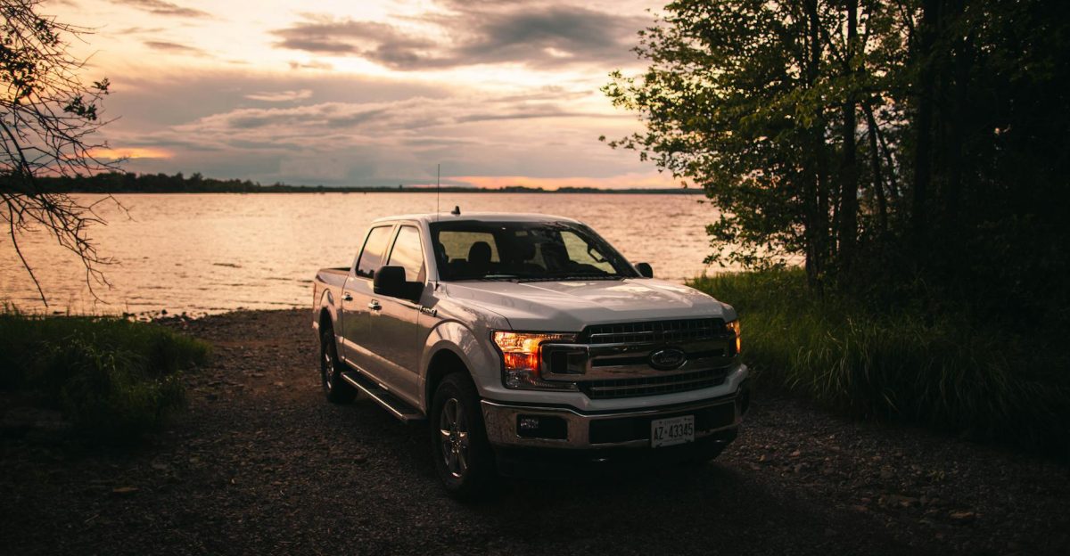 Scenic view of a Ford F-150 truck by a lakeshore in Quebec City at sunset showcasing the beauty of rural Canada