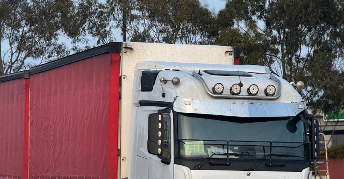 White and red semi truck parked outdoors at logistics hub ready for transportation