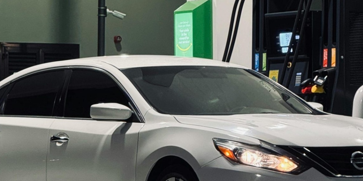 White sedan at a well-lit gas station at night, showcasing nighttime refueling.