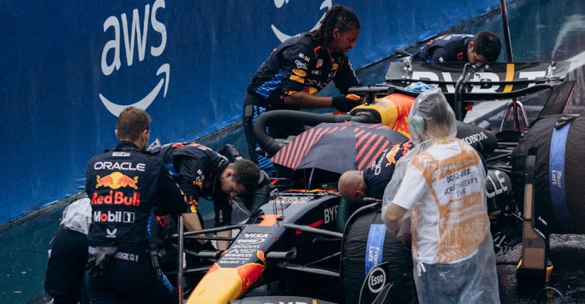 Intense Formula 1 pit stop during a rain-soaked race showcasing teamwork and precision