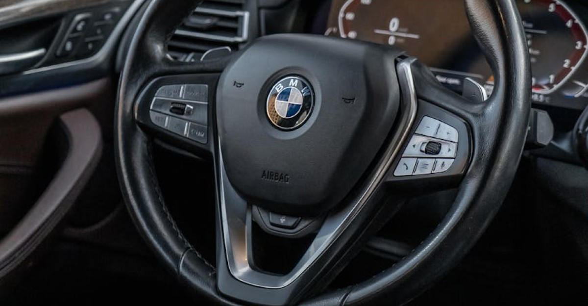 Close-up of a BMW X3 luxury SUV interior showcasing the leather-wrapped steering wheel and modern dashboard