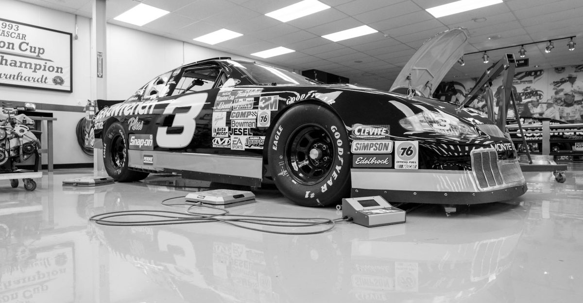 Black and white image of a classic NASCAR race car inside a workshop showcasing vintage design