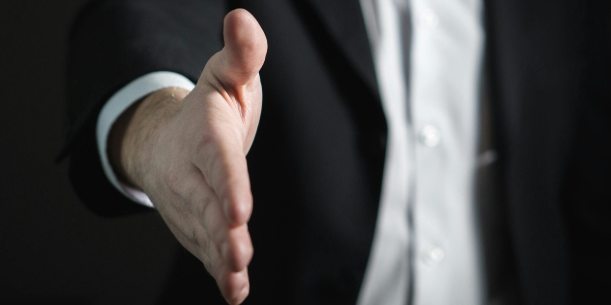 Close-up of a businessman extending hand for a handshake, symbolizing agreement and partnership.
