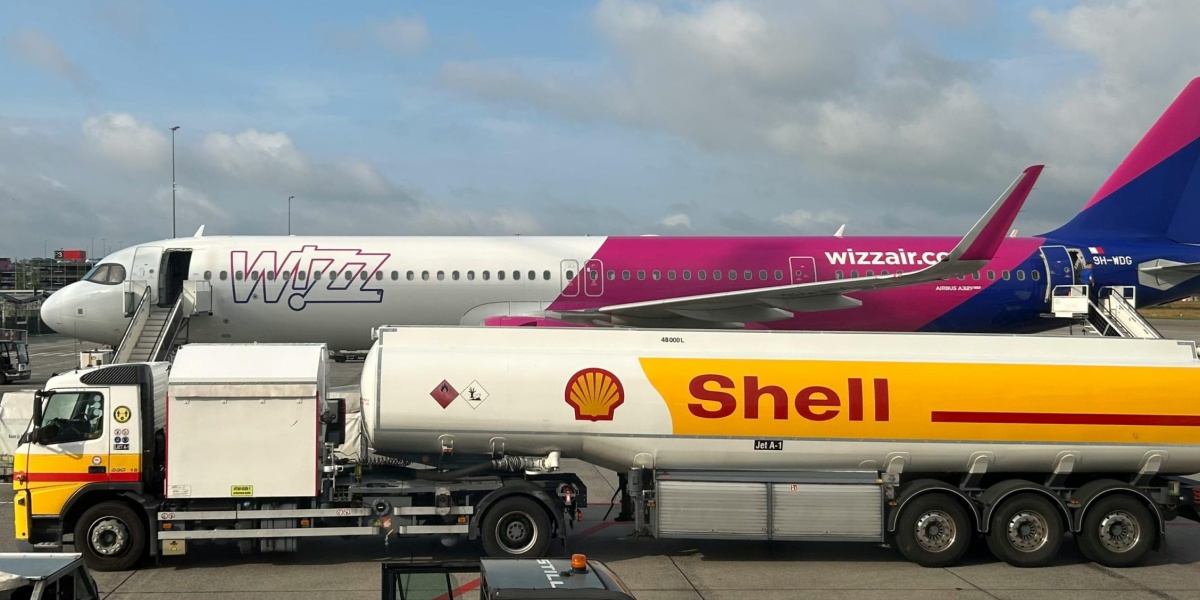 A plane being refueled by a Shell fuel truck on a sunny day at the airport.