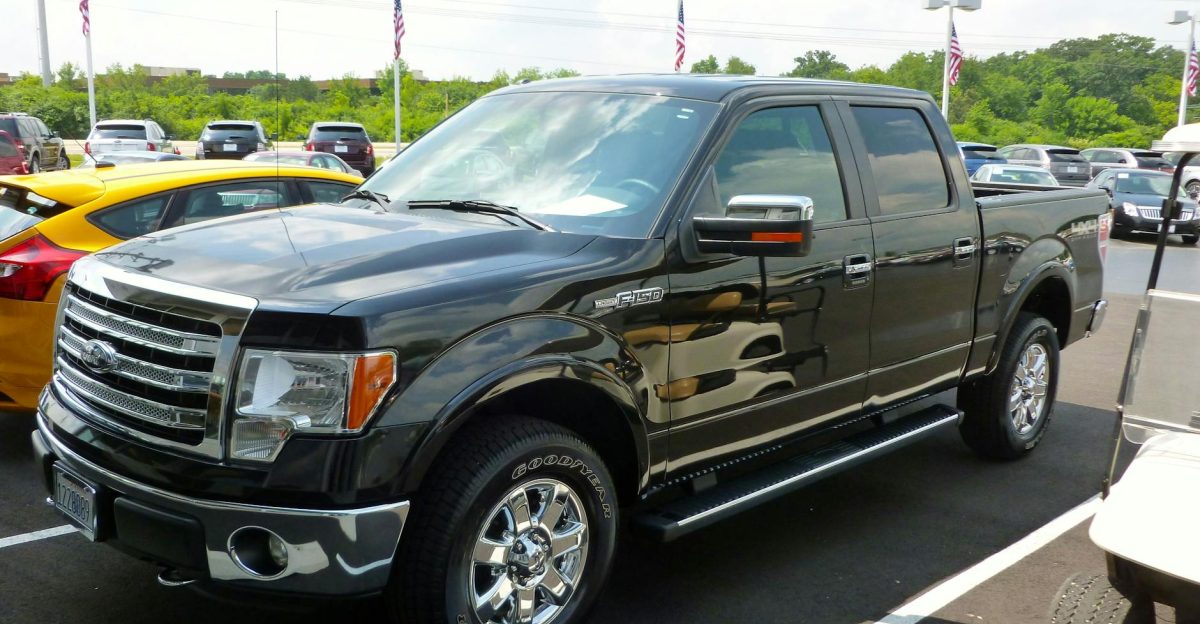 Black Ford F-150 pickup truck displayed at an outdoor dealership lot on a sunny day