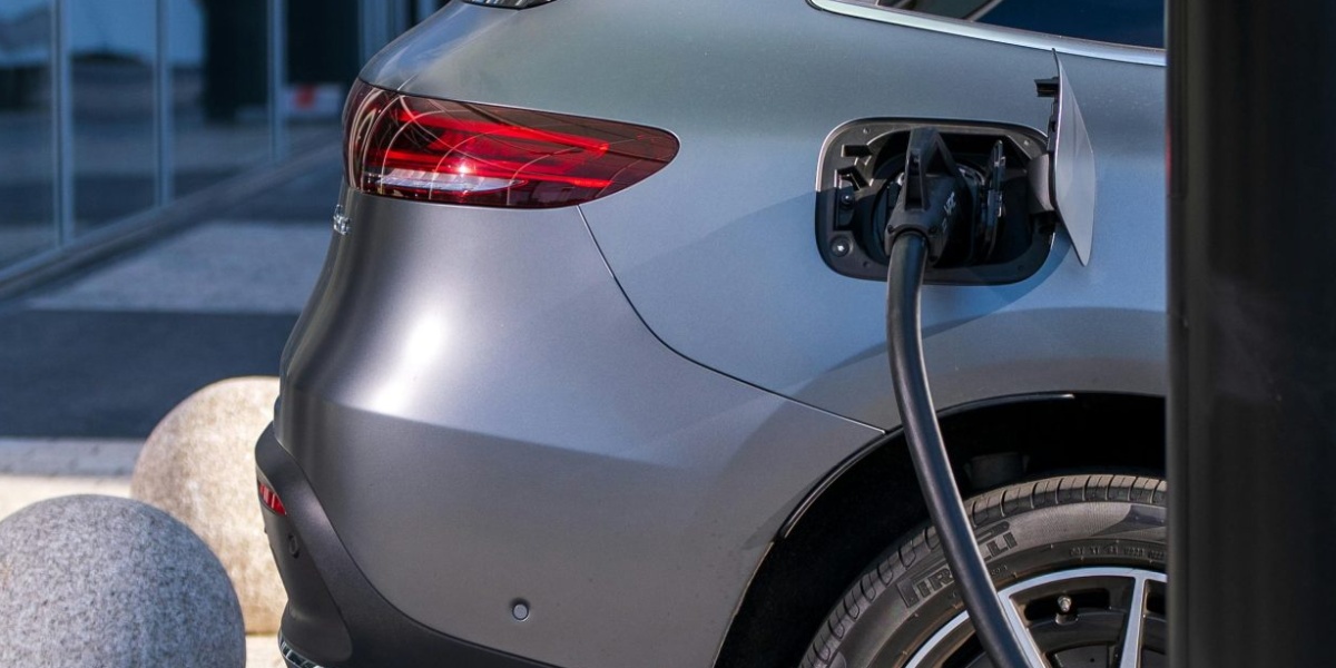 A silver electric car charging at an urban station, highlighting sustainable living in a modern cityscape.