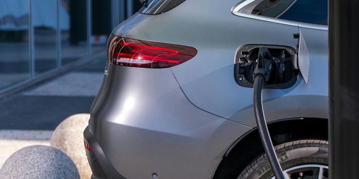 A silver electric car charging at an urban station, highlighting sustainable living in a modern cityscape.