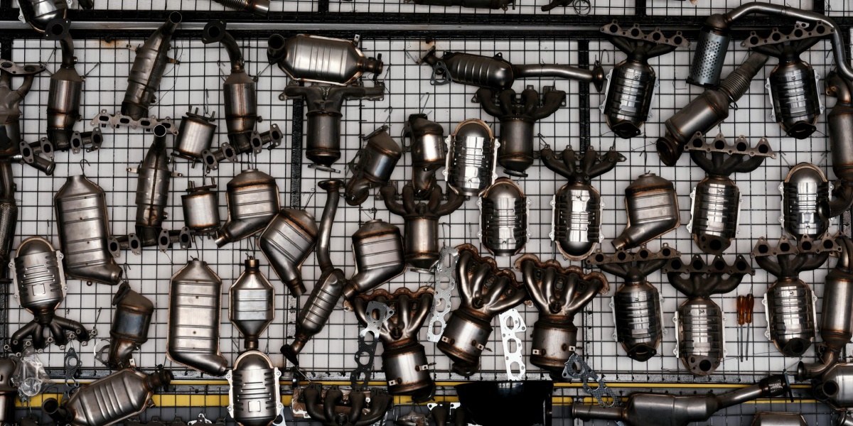 An array of automotive exhaust parts displayed on a grid wall in an industrial garage setting.