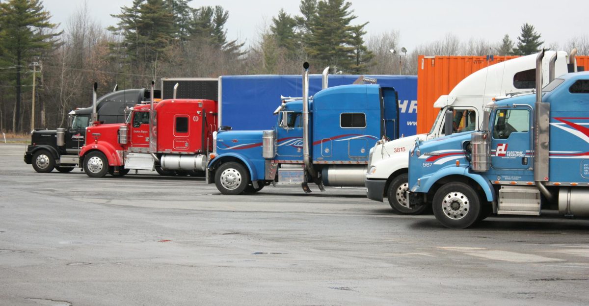 Multiple semi trucks in vivid colors parked outdoors in a spacious lot