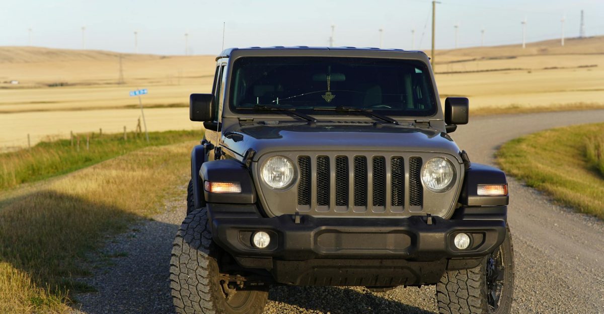 Front view of a Jeep Wrangler on a gravel road in a rural Canadian landscape with wind turbines