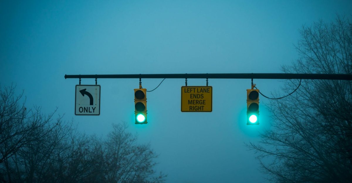 Green traffic lights on a misty evening at an intersection with road signs