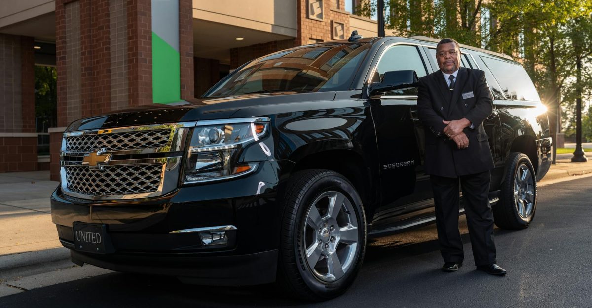 Chauffeur standing confidently next to a black SUV offering luxury transportation service