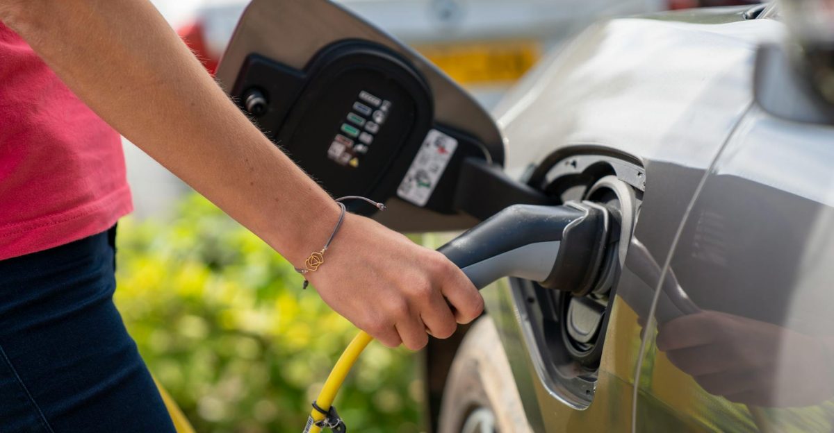 Close-up of a person plugging in an electric car at a charging station outdoors