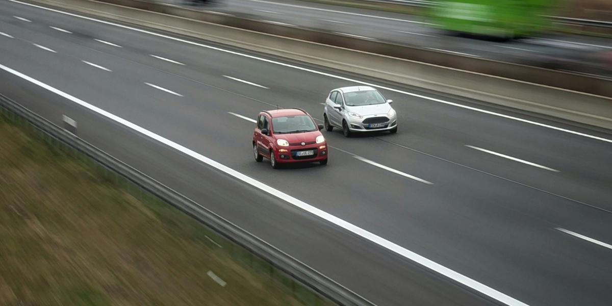 Two cars moving fast on a highway, showcasing speed and travel in motion.