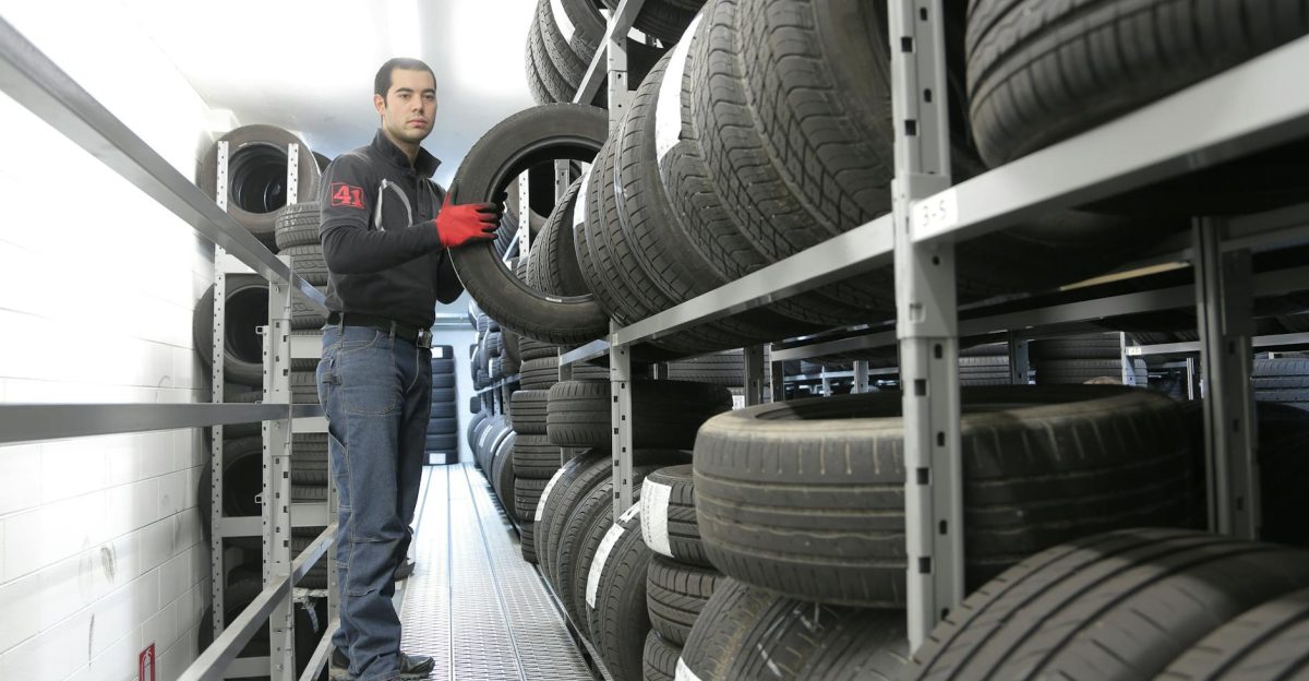 Mechanic places a tire on a rack in an indoor warehouse storage facility