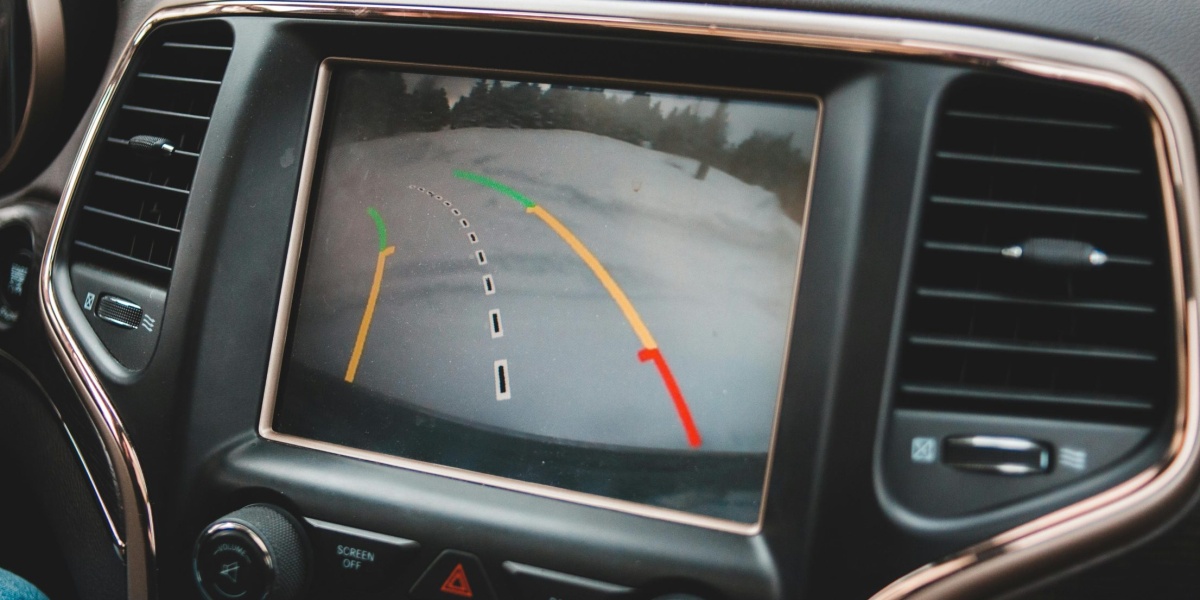 Close-up of a car's dashboard showing a rearview camera display for parking assistance.