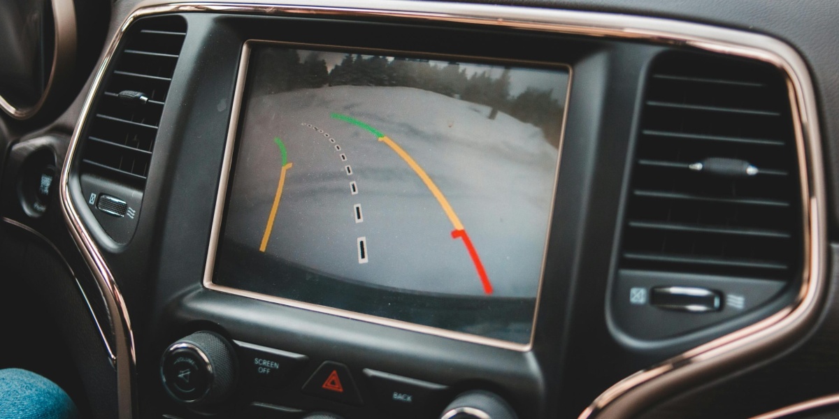Close-up of a car's dashboard showing a rearview camera display for parking assistance.