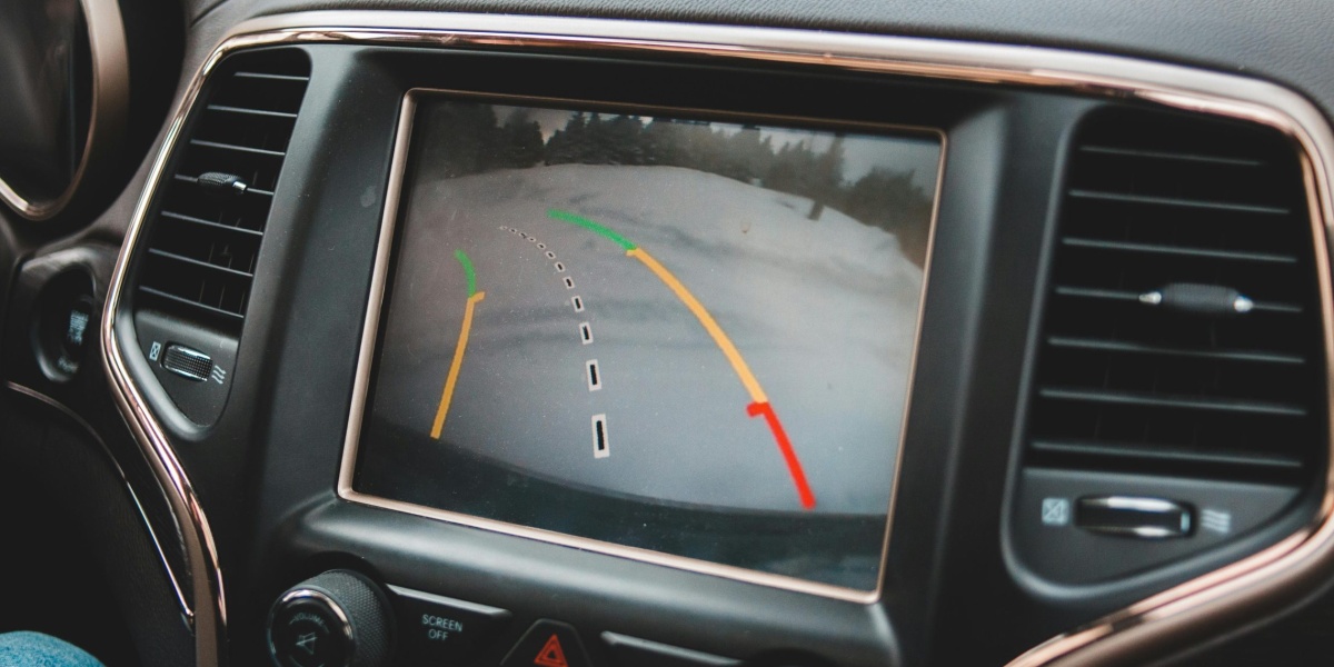 Close-up of a car's dashboard showing a rearview camera display for parking assistance.