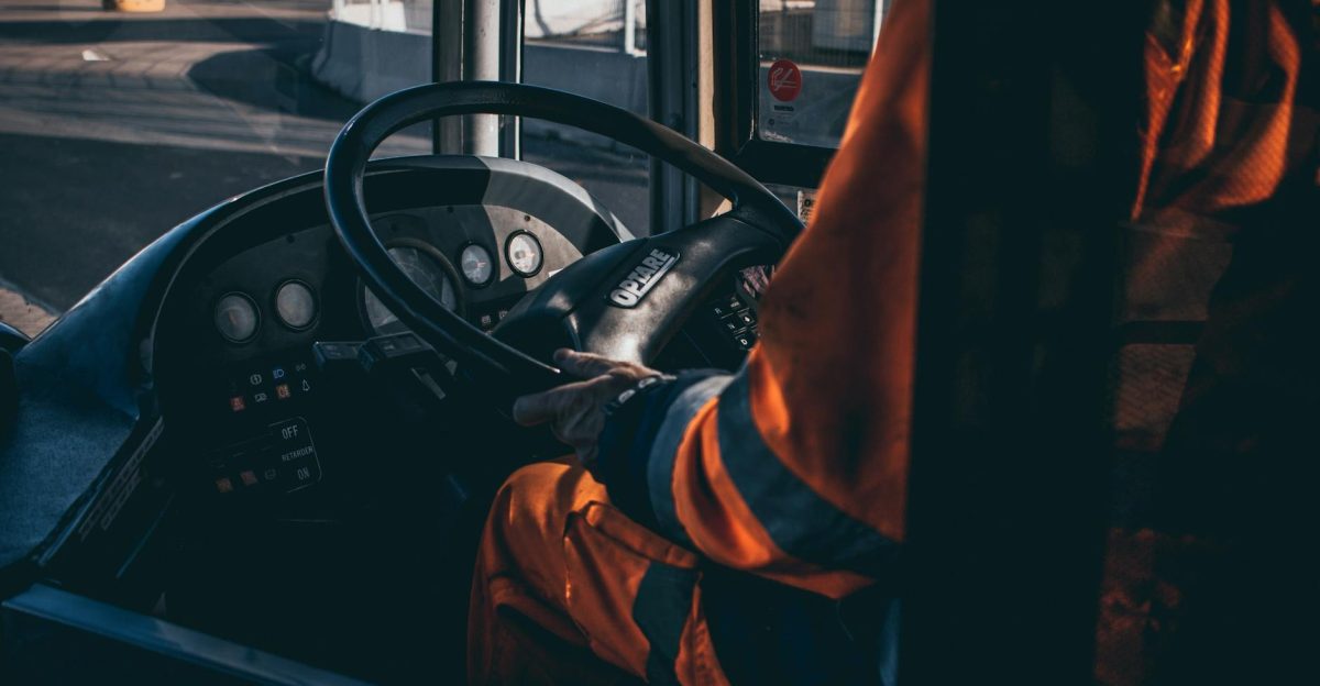 Bus driver operating vehicle from the cockpit in an industrial setting showcasing control and focus