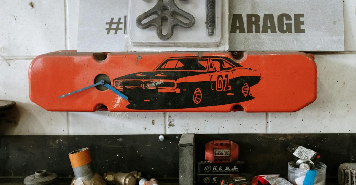 Red car part with a clock on a garage wall surrounded by tools and auto parts