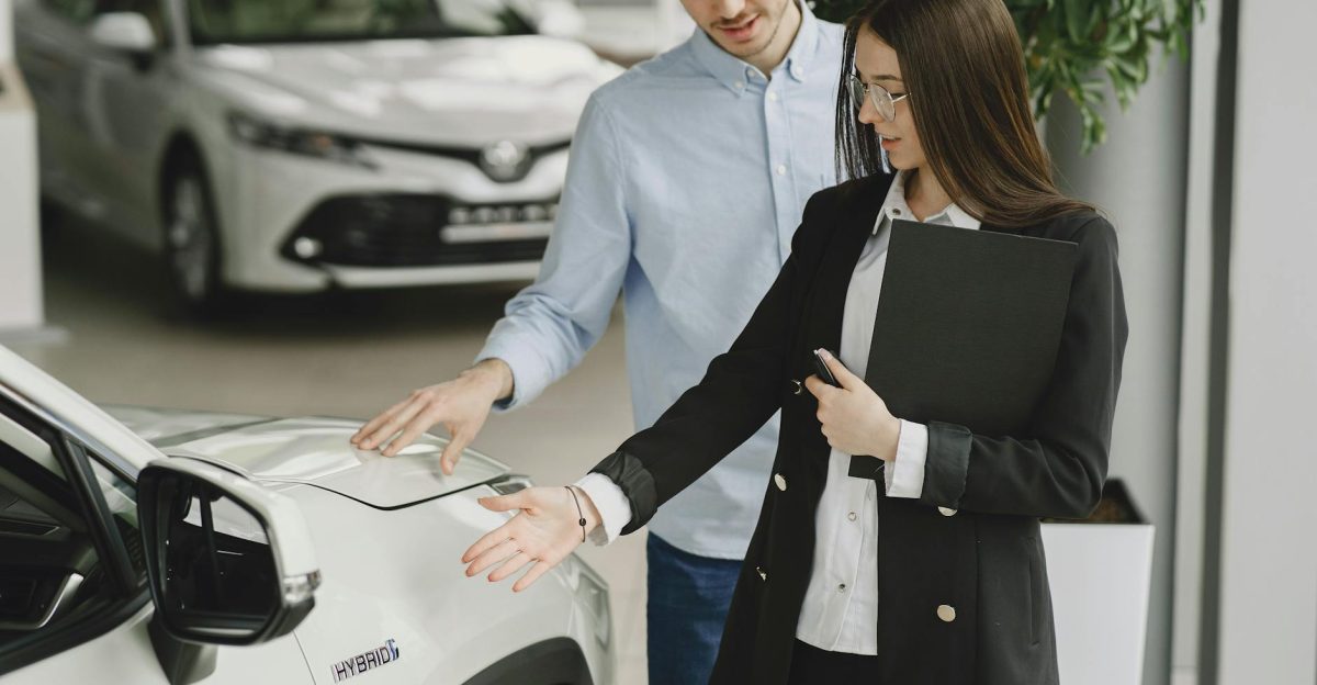 A man and saleswoman discussing a hybrid vehicle s features in an indoor showroom