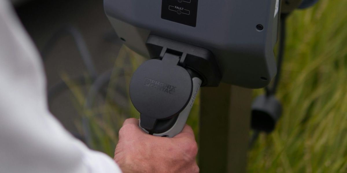 Close-up of a hand connecting an electric vehicle at a charging station in Christchurch, New Zealand.
