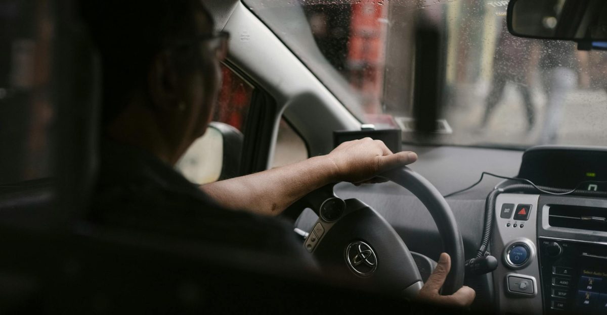 Back view of crop anonymous man in eyeglasses driving car in rainy day