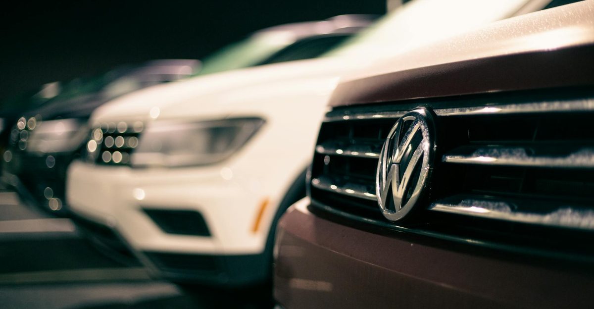 Front bumpers of expensive prestige automobiles at market retailing new cars at night