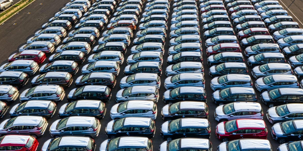 From above of many modern new automobiles placed on asphalt near factory in daytime