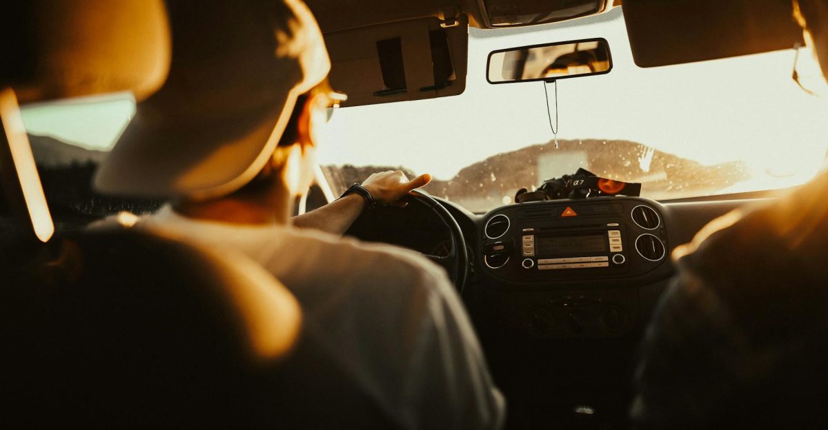 Man driving car with passenger at sunset capturing warm sunlit atmosphere