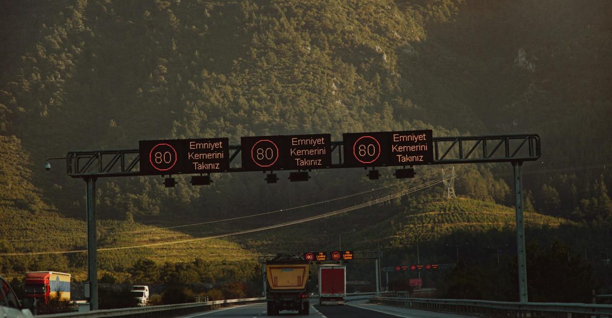 Highway with speed limit signs against a mountainous backdrop and low traffic
